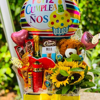 Cesta con girasoles, osito, dulces y globo de cumpleaños.
