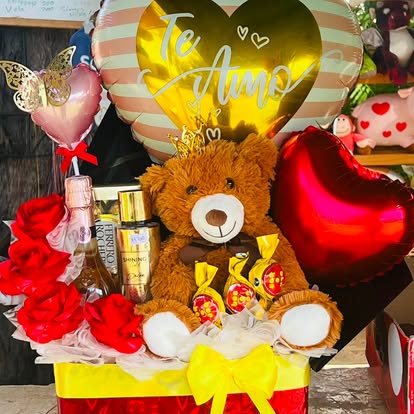 Cesta con osito, rosas rojas, bombones y globos de corazón. Consulta los complementos de la presentación.