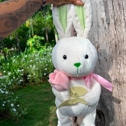 Peluche blanco con orejas largas y lazos de colores suaves.