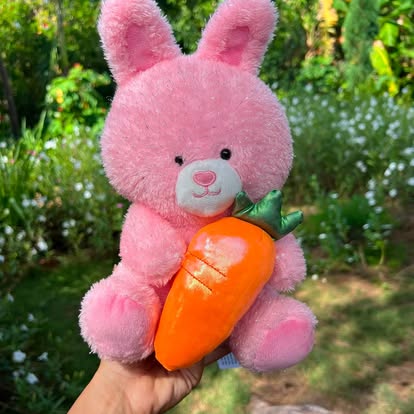 Peluche de conejito rosa sosteniendo una zanahoria.