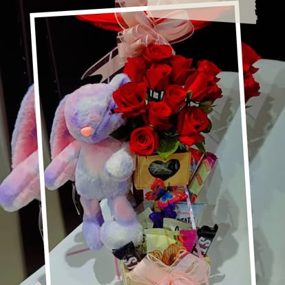 Un peluche lila junto a flores