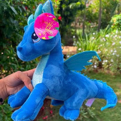Peluche de dragón azul con alas y detalles de colores.