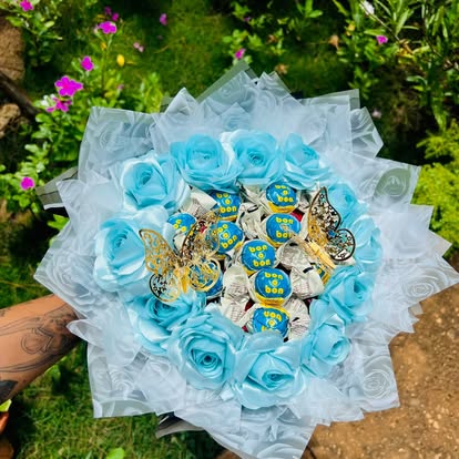 Ramo de flores decorativas azules con bombones y mariposas doradas.