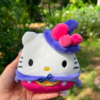 Peluche de Hello Kitty con sombrero y capa morados.