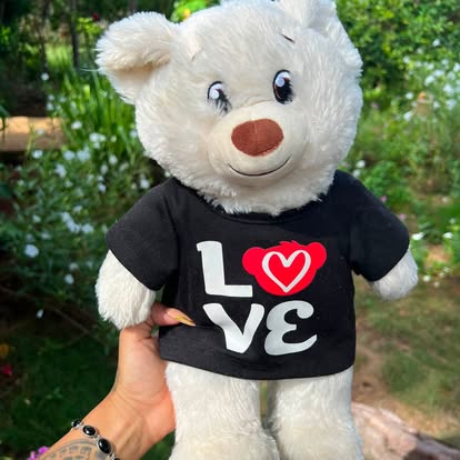 Osito blanco con camiseta negra y diseño de corazón.
