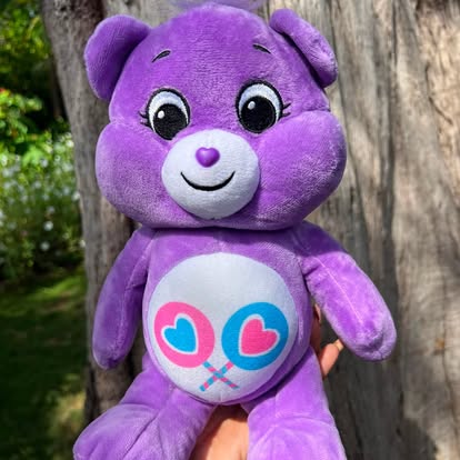 Peluche morado con un dibujo de corazones en la barriga.
