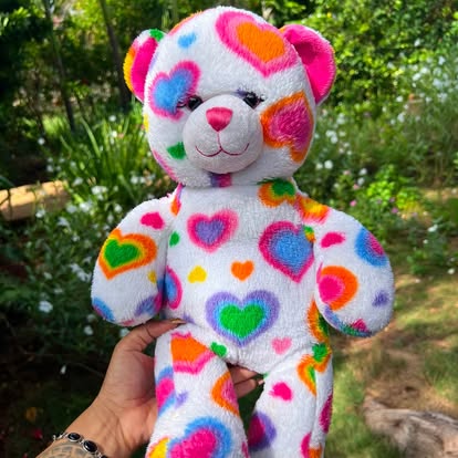 Peluche blanco cubierto con corazones de colores.