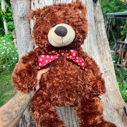 Peluche de osito marrón con una pajarita de colores.