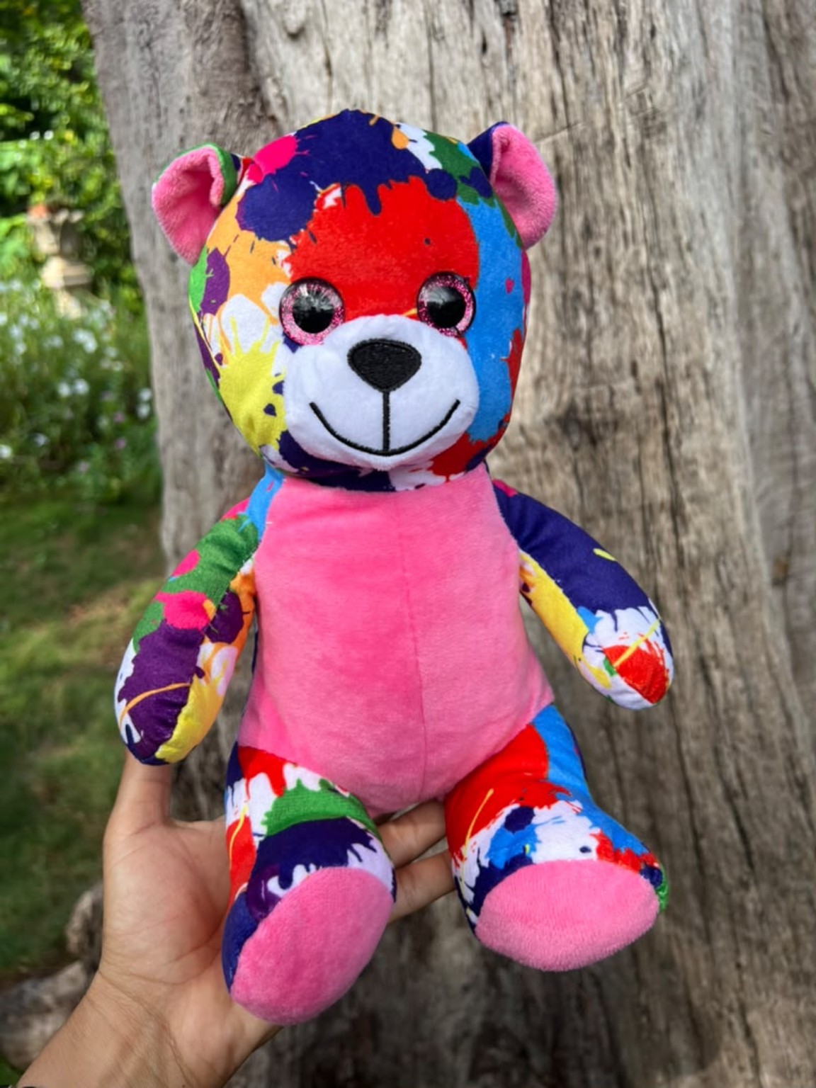 Peluche de perrito con manchas de colores y barriga rosa.