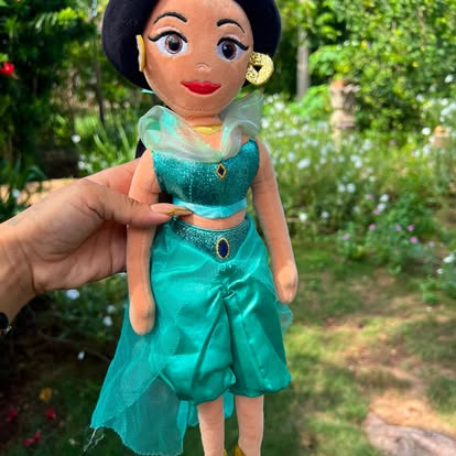 Muñeca de peluche de princesa con cabello oscuro y vestido turquesa.