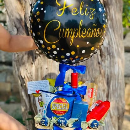 Detalle de cumpleaños con snacks, globo negro y presentación en azul.