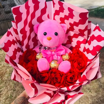 Ramo de rosas rojas, osito rosa y bombones, con envoltura rosa y roja.