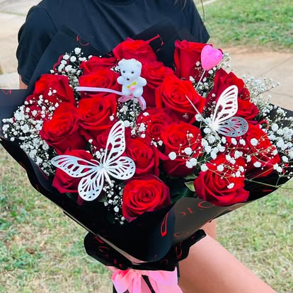 Ramo de rosas rojas con pequeñas flores blancas, mariposas y envoltura negra.