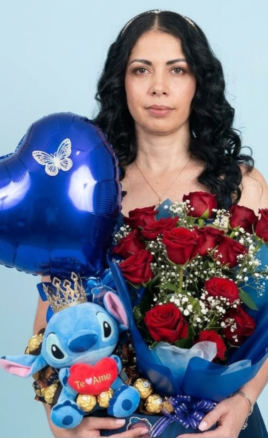 Regalo con rosas rojas, flores blancas pequeñas, peluche de Stitch, bombones y un globo de corazón azul.