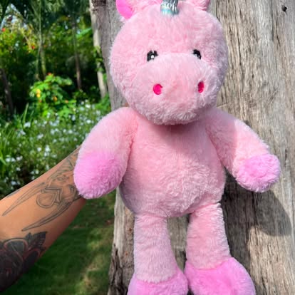 Peluche de unicornio rosa con un pequeño cuerno brillante.